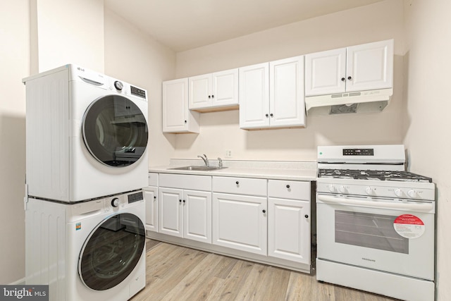 kitchen with sink, light wood-type flooring, white cabinetry, white range with gas stovetop, and stacked washer / dryer