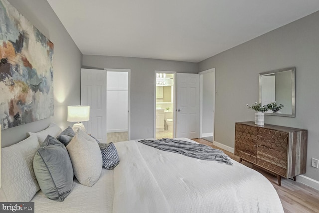 bedroom with ensuite bathroom, a walk in closet, and light wood-type flooring