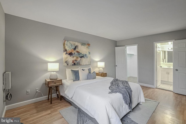 bedroom featuring a closet, ensuite bath, a spacious closet, and light hardwood / wood-style flooring