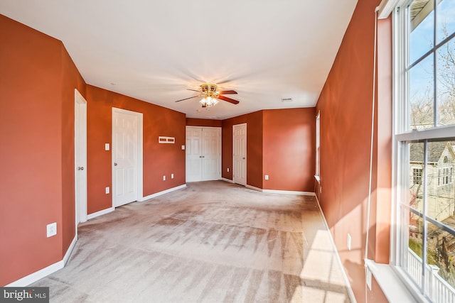 spare room featuring ceiling fan, light carpet, and a wealth of natural light