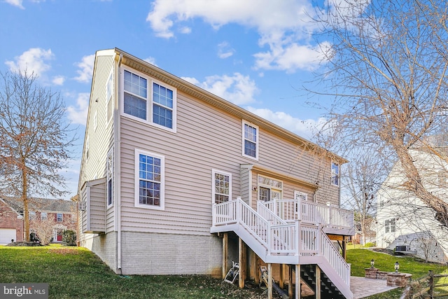 rear view of property with a wooden deck and a lawn