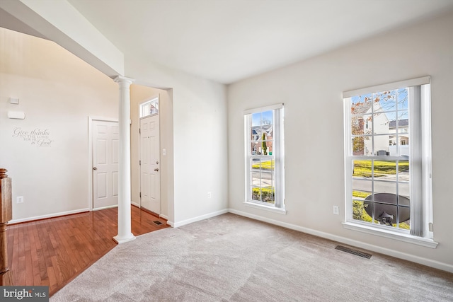 spare room with light wood-type flooring, ornate columns, and plenty of natural light