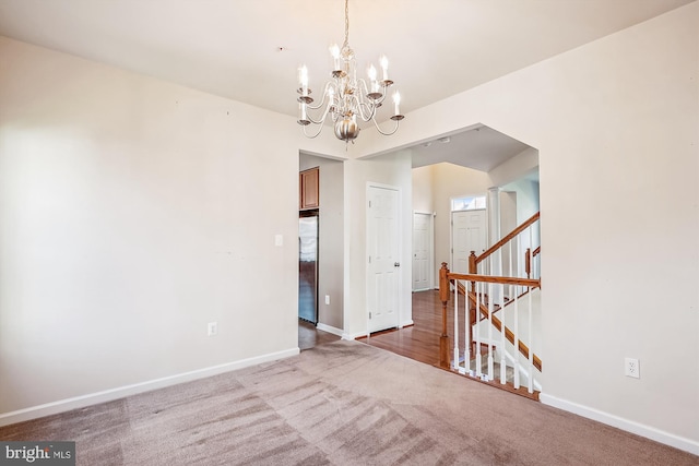 carpeted spare room featuring a notable chandelier