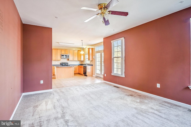 unfurnished living room with ceiling fan and light colored carpet