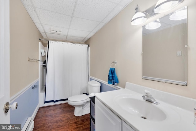 full bathroom featuring a drop ceiling, baseboard heating, wood-type flooring, toilet, and vanity