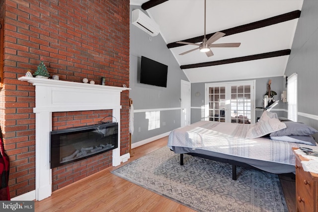 bedroom featuring lofted ceiling with beams, a brick fireplace, ceiling fan, light hardwood / wood-style floors, and a wall unit AC