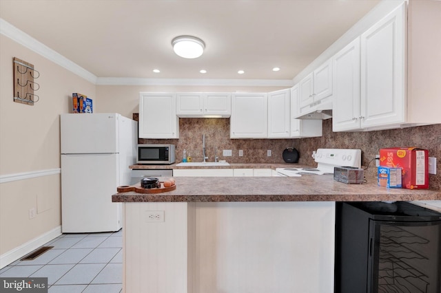 kitchen with white appliances, white cabinets, sink, light tile patterned floors, and kitchen peninsula