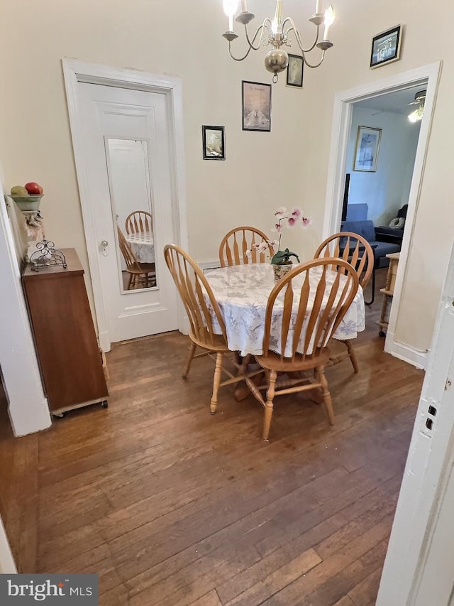 dining space with dark wood-type flooring and a notable chandelier