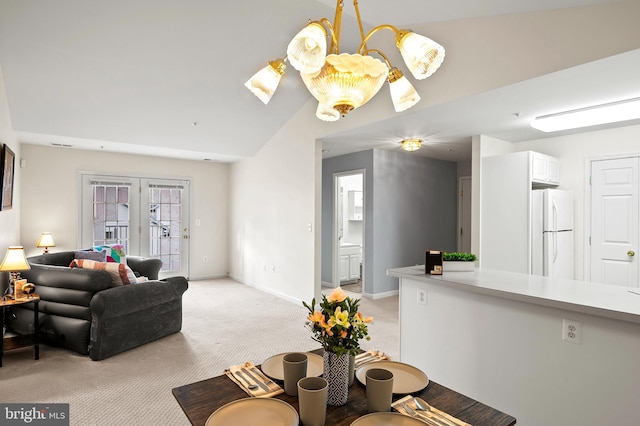 carpeted living room featuring a chandelier and vaulted ceiling