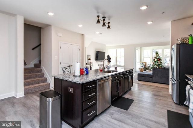 kitchen with sink, a center island with sink, light hardwood / wood-style flooring, and appliances with stainless steel finishes