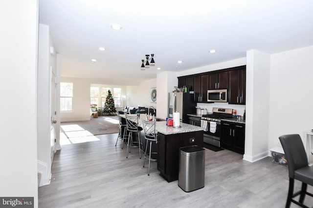 kitchen featuring sink, a kitchen bar, a kitchen island with sink, light hardwood / wood-style floors, and stainless steel appliances