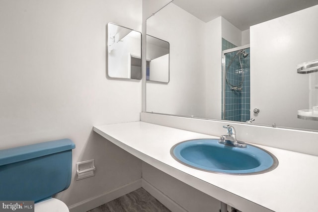 bathroom with wood-type flooring, toilet, vanity, and a tile shower