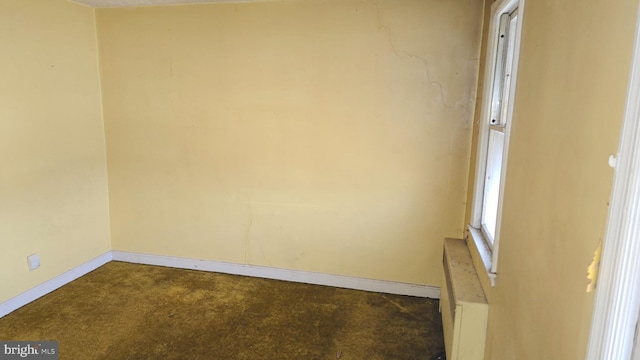 unfurnished room featuring radiator and carpet