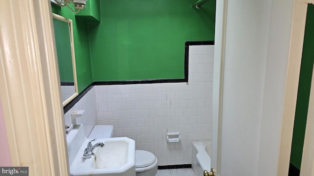 bathroom with tile patterned floors, toilet, tile walls, and sink