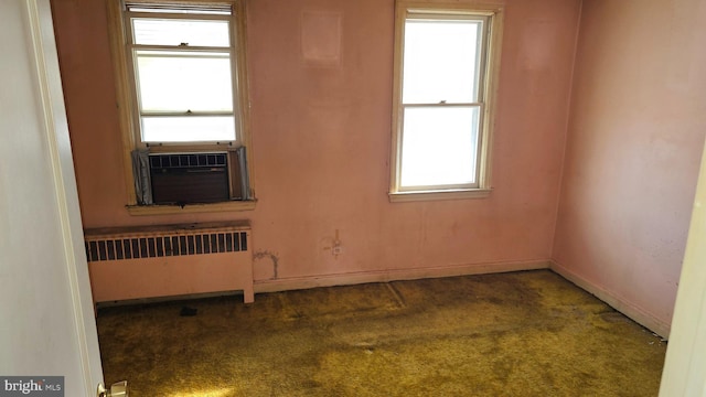 spare room with dark colored carpet, radiator heating unit, and cooling unit