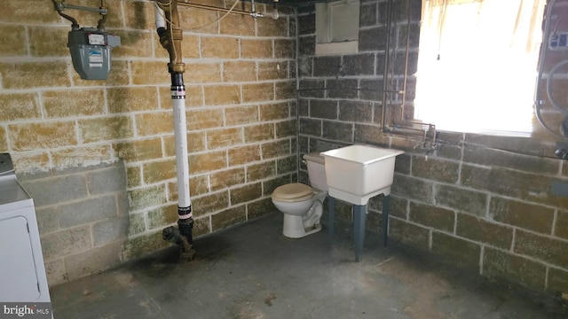 bathroom with toilet, washer / dryer, and concrete flooring