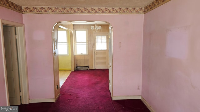 hallway featuring dark carpet and a textured ceiling