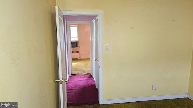 hall featuring dark colored carpet and radiator