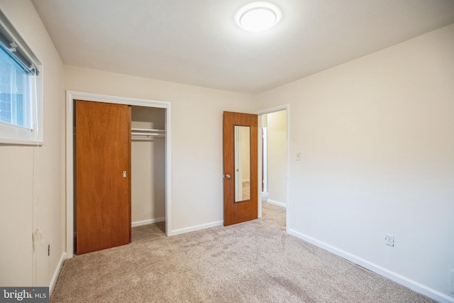 unfurnished bedroom with light colored carpet and a closet