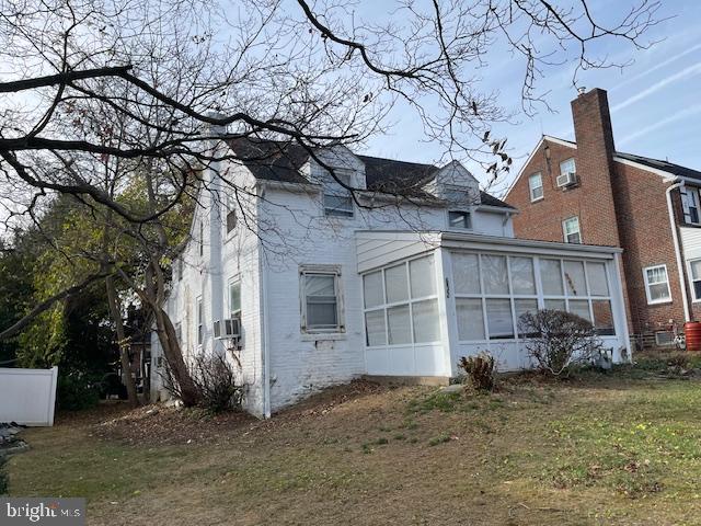 view of side of property featuring a yard, cooling unit, and a sunroom