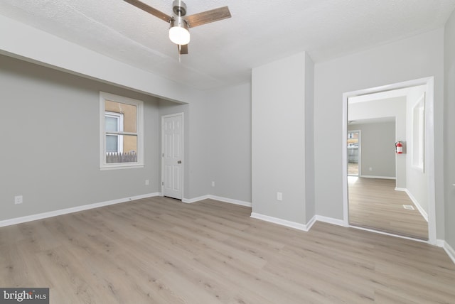 spare room with a textured ceiling, light wood-type flooring, and ceiling fan