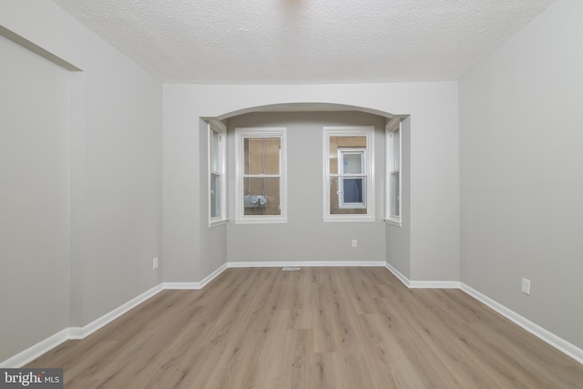 unfurnished room featuring a textured ceiling and light wood-type flooring