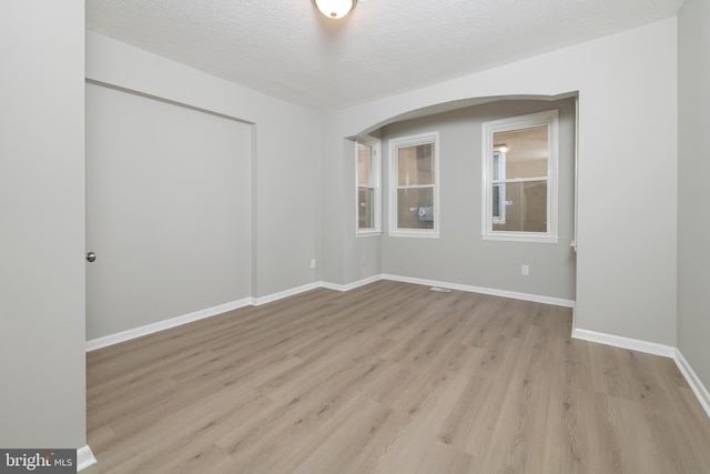 spare room with a textured ceiling and light hardwood / wood-style flooring