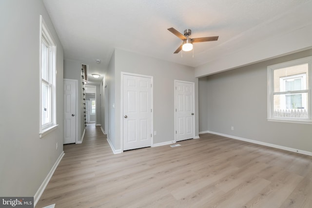 unfurnished bedroom with ceiling fan, light wood-type flooring, a textured ceiling, and multiple windows