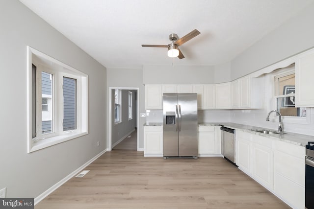 kitchen featuring backsplash, sink, light stone countertops, appliances with stainless steel finishes, and light hardwood / wood-style floors