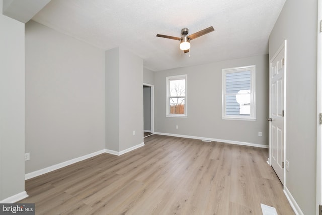 empty room with a textured ceiling, light hardwood / wood-style floors, and ceiling fan