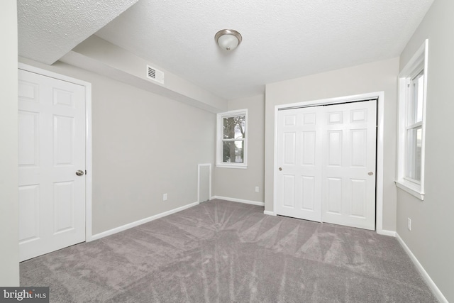 unfurnished bedroom with a textured ceiling, carpet floors, and a closet