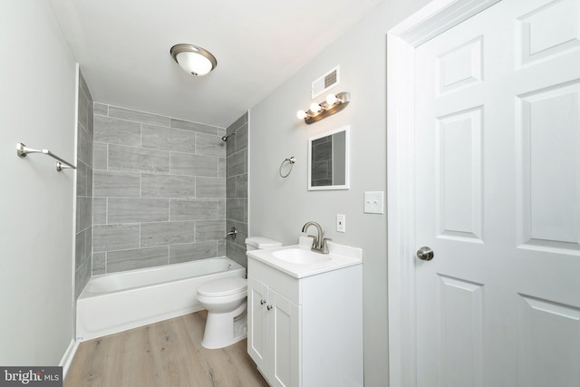 full bathroom featuring hardwood / wood-style floors, vanity, toilet, and tiled shower / bath combo