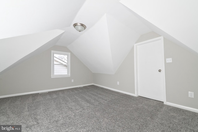 additional living space featuring dark carpet and vaulted ceiling