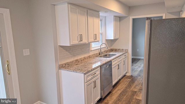 kitchen with dark hardwood / wood-style flooring, backsplash, stainless steel appliances, sink, and white cabinets