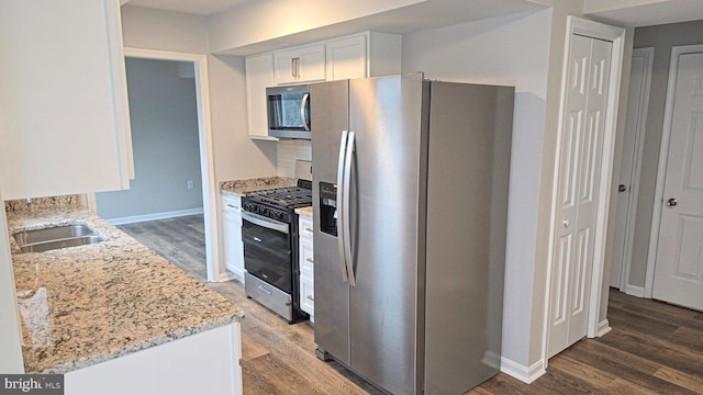 kitchen featuring sink, dark wood-type flooring, light stone counters, white cabinets, and appliances with stainless steel finishes