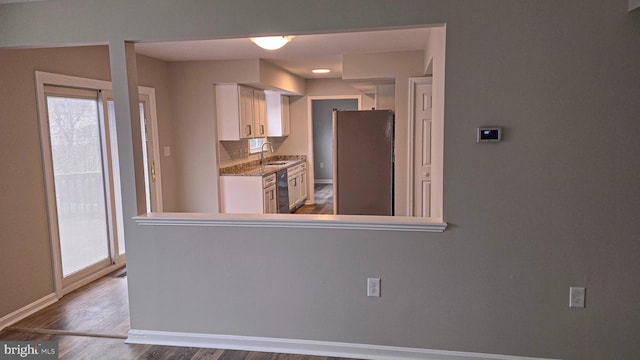 kitchen featuring stainless steel refrigerator, sink, decorative backsplash, white cabinets, and hardwood / wood-style flooring