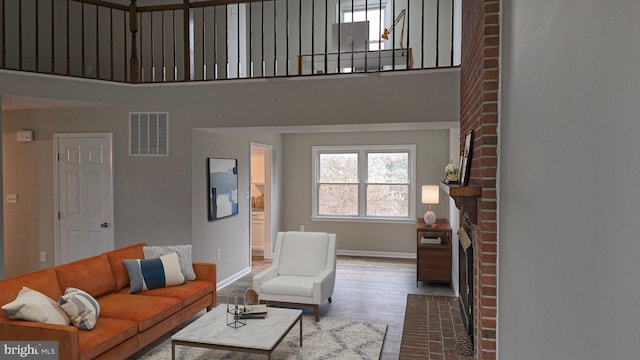 living room with a fireplace, a towering ceiling, and wood-type flooring