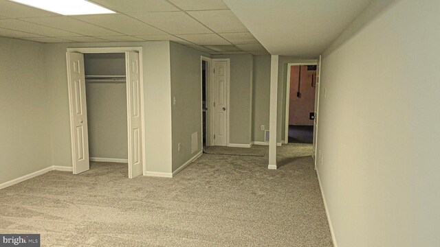 unfurnished bedroom with a drop ceiling, light colored carpet, and a closet