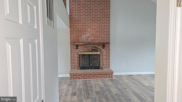 unfurnished living room featuring wood-type flooring and a brick fireplace