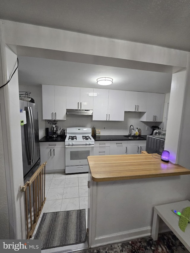 kitchen with white cabinets, sink, stainless steel fridge, white gas stove, and kitchen peninsula