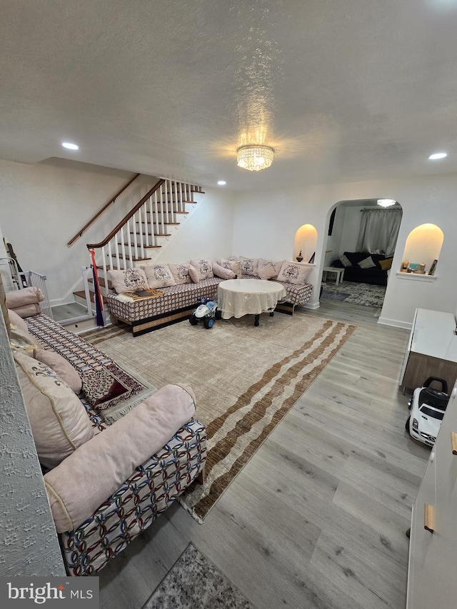 living room with hardwood / wood-style flooring, a textured ceiling, and an inviting chandelier