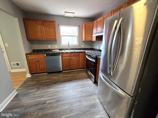 kitchen with dark stone counters, sink, stainless steel appliances, and dark hardwood / wood-style floors