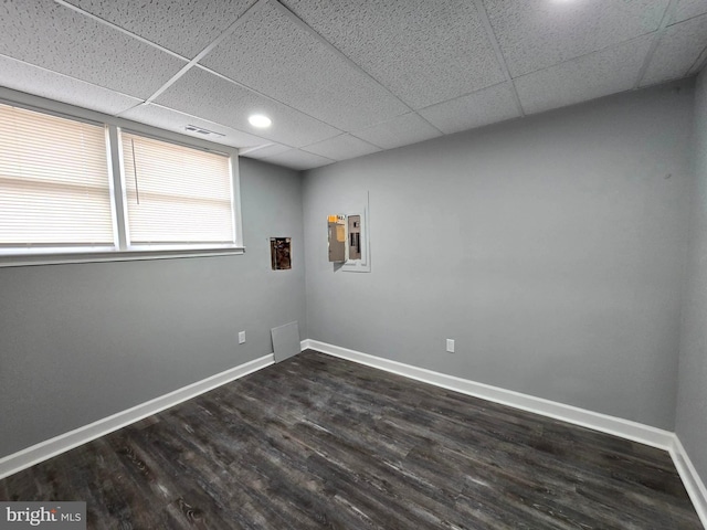 spare room with a drop ceiling, dark hardwood / wood-style flooring, and electric panel