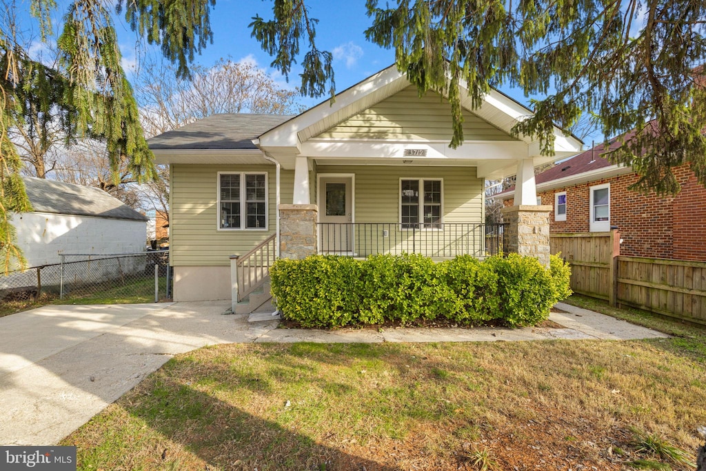 bungalow-style house featuring covered porch and a front lawn