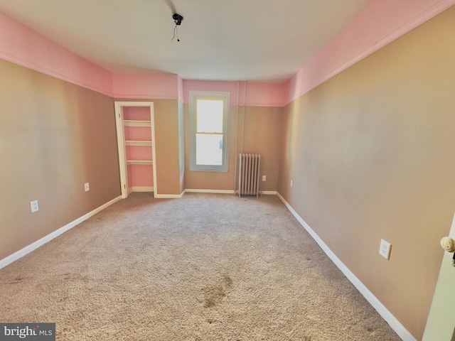 carpeted spare room featuring radiator heating unit