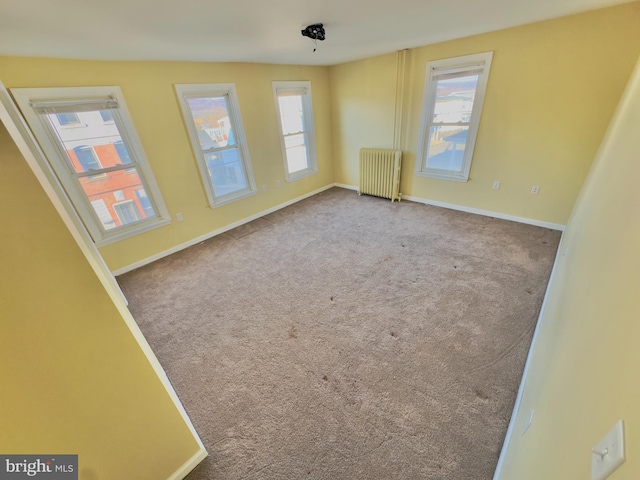 carpeted empty room featuring radiator heating unit