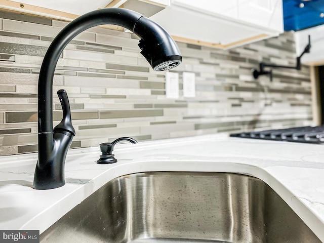 interior details featuring tasteful backsplash, light stone counters, and sink