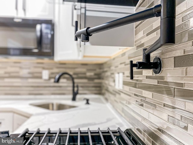 room details featuring white cabinets, sink, and backsplash