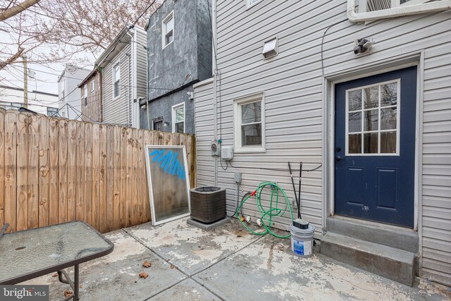 view of patio with entry steps, central AC unit, and fence