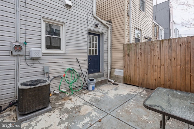 property entrance with cooling unit, a patio, and fence